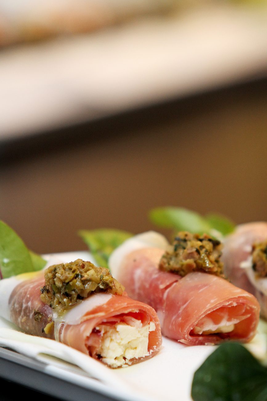 A canape of prosciutto rolled around feta and topped with olive tapenade