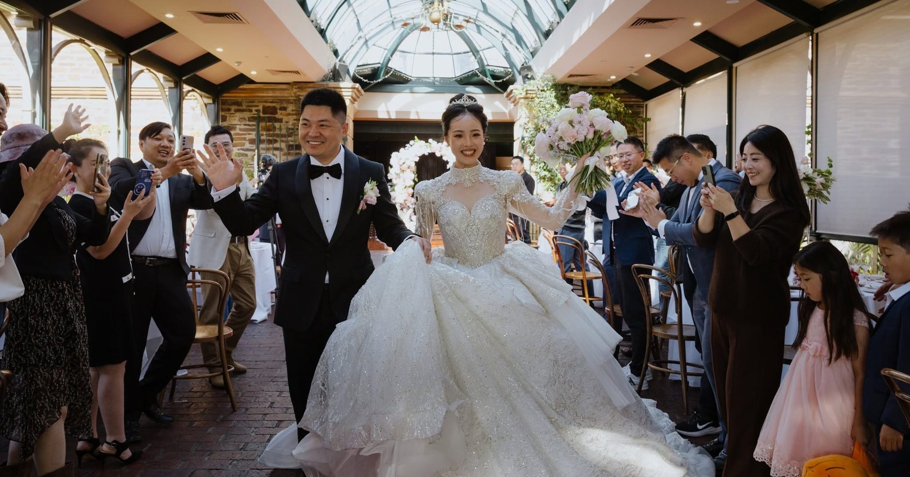 A bride and groom making their entrance through the Conservatory as guests cheer