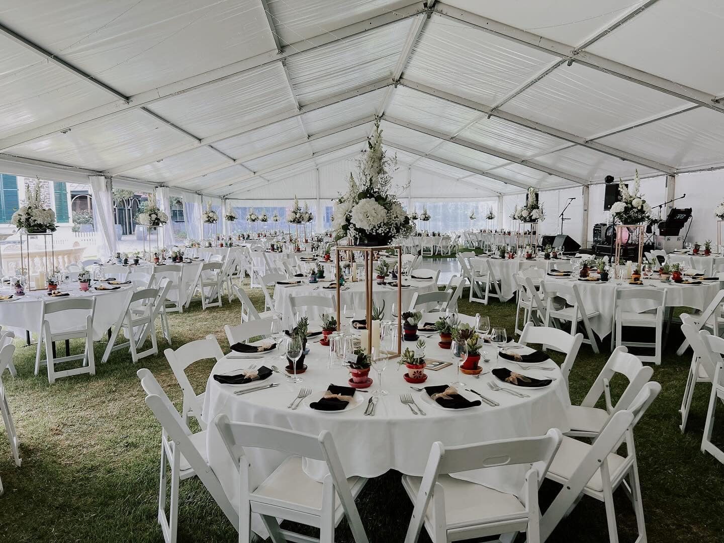 Inside the Marquee on the front lawns, round tables dressed with white linen and tall floral centrepieces, a stage set for the band